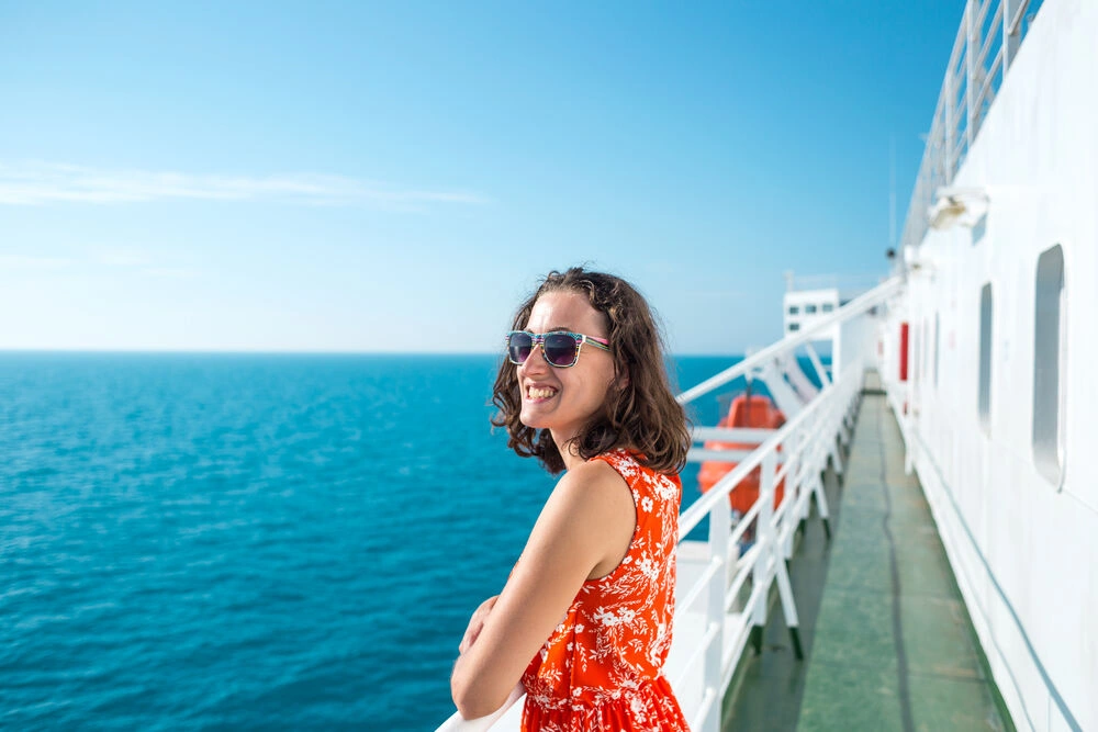 A woman is sailing on a cruise ship, a girl is standing near the fence on a ship and looking at the sea